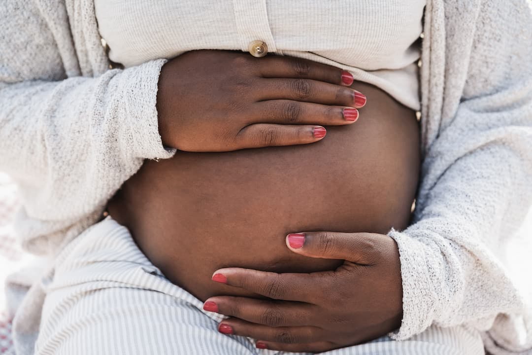 Pregnant black woman holding her belly, pregnancy, fertility