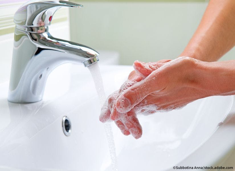 close up of a person washing their hands with soap and water in a sink