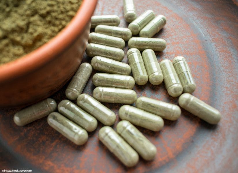 Supplement kratom green capsules and powder on brown plate